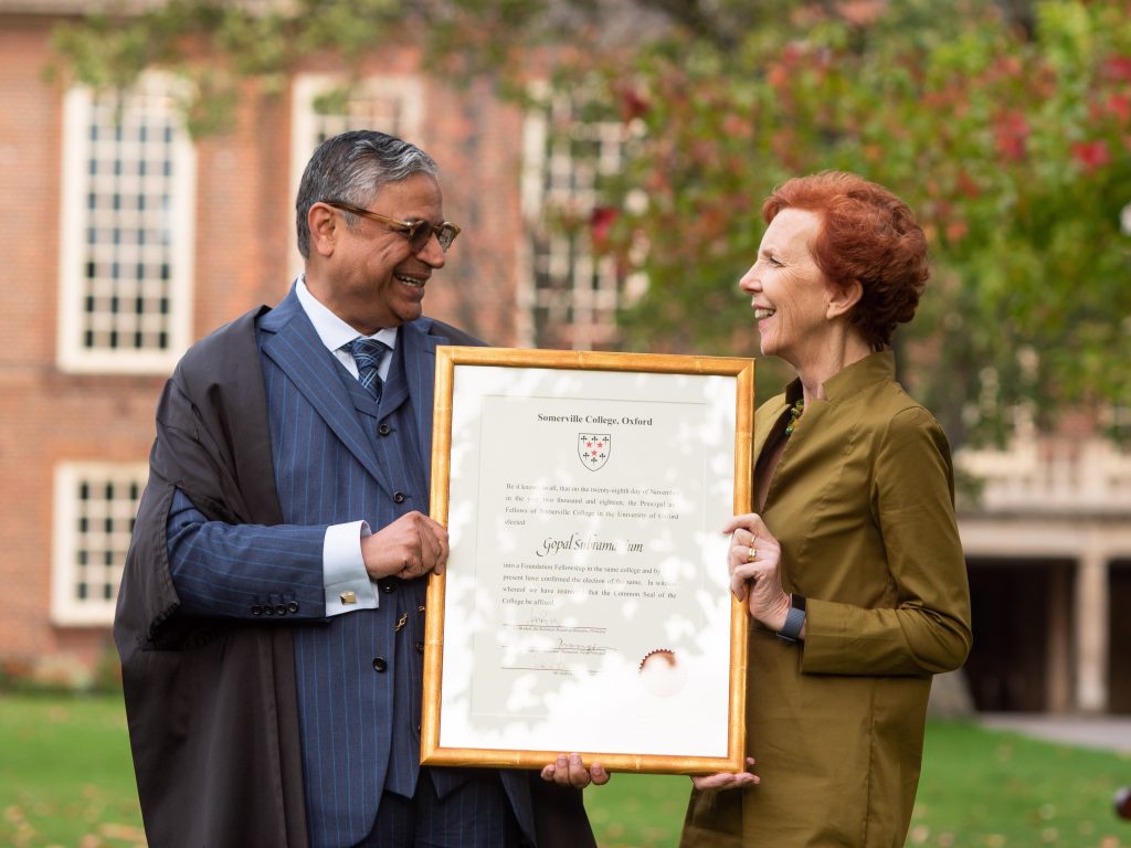 Gopal Subramanium receives a certificate of his Fellowship from Principal Jan Royall while standing on the quadrangle