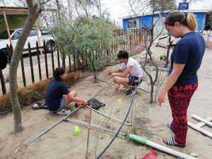 three students in Peru, including somerville student eleanor thompson, build an irrigation system using iron piping, outdoors