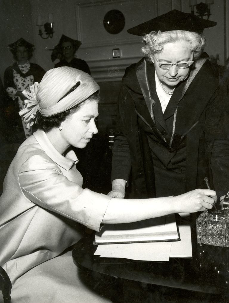 The Queen with then-librarian Norma Russell, signing the Ruskin Birthday Book also signed by Queen Mary, Charles III and Ruskin himself.