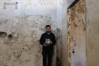 Ammar in Syria in 2025, holding his book Domicide. Photo credit: Anas Altaweel.