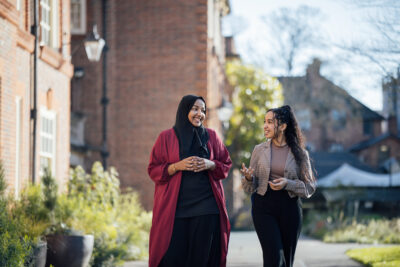 Two young women walk together through Somerville college quad