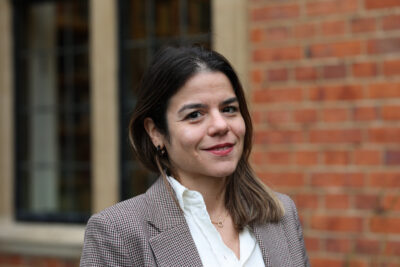 A woman wearing a shirt and jacket smiles at the camera