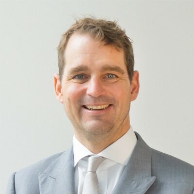 A man in a suit smiles at the camera