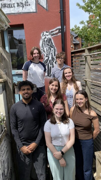 A group of young adults stand together, smiling at the camera.