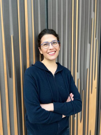 A woman smiles at the camera with her arms folded