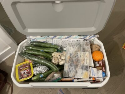 A large crate filled with various different foods including lots of cucumbers and mushrooms.